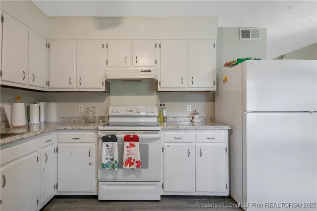 a kitchen with granite countertop white cabinets and white appliances