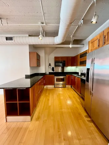 a view of kitchen with stainless steel appliances wooden floor and large windows