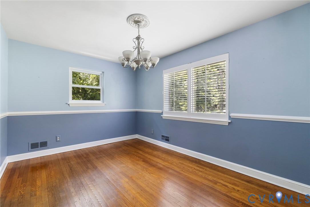 7644 Cherokee Road Richmond, VA 23225 - Photo 8 of 31 Empty room with a chandelier and hardwood / wood-s
