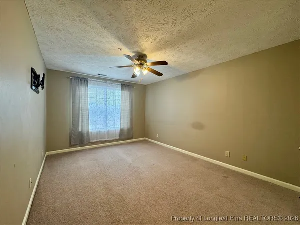 an empty room with a ceiling fan and carpet
