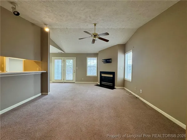 wooden floor in an empty room with a fireplace and a ceiling fan
