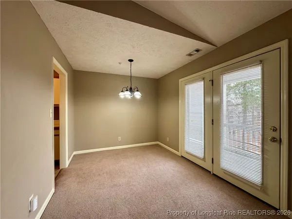 an empty room with chandelier fan and windows