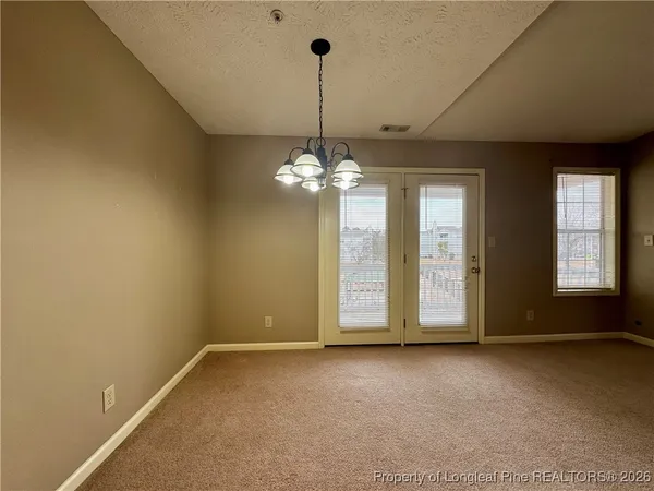 a view of a livingroom with a chandelier fan and windows