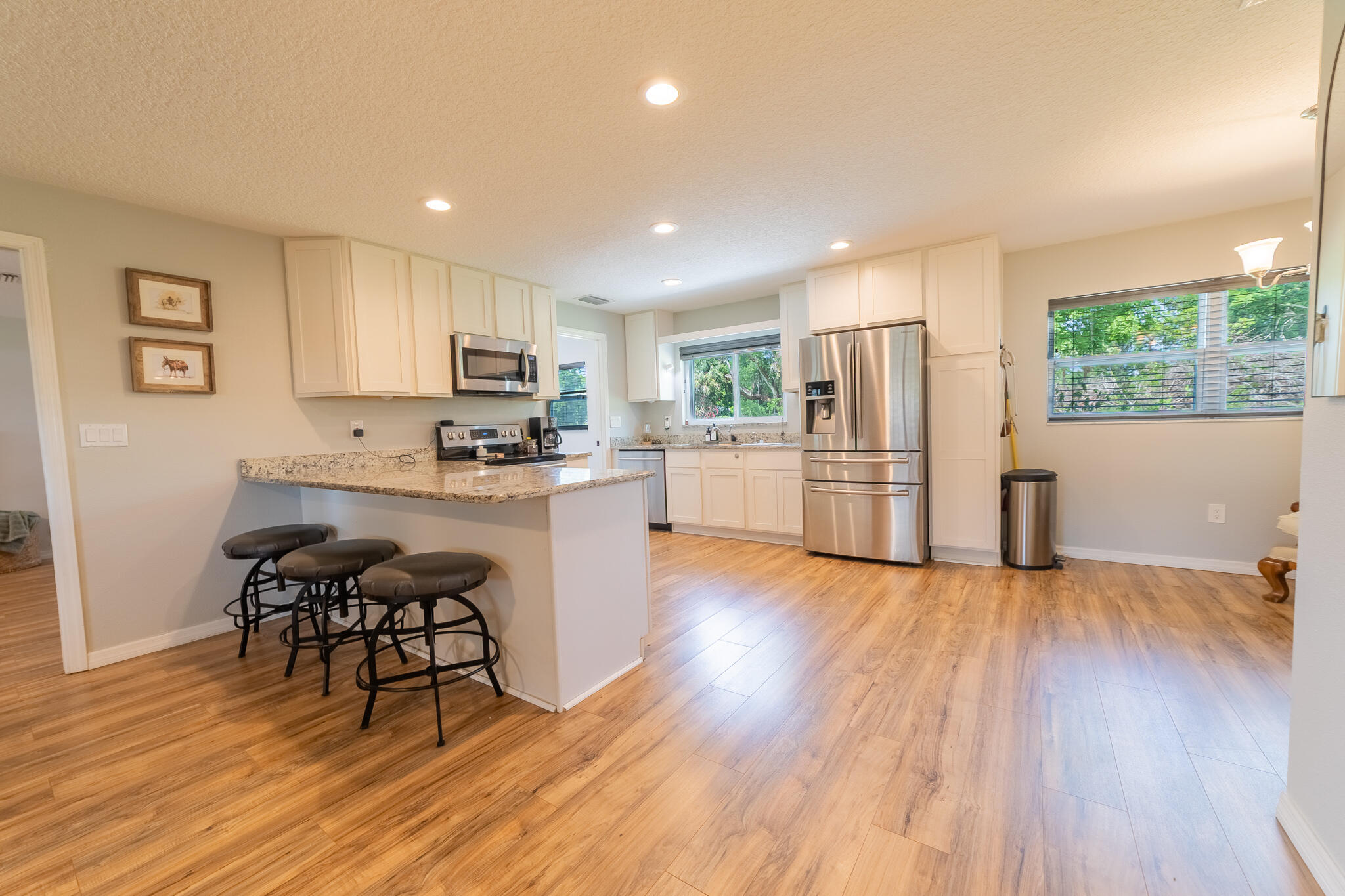 2675 Southwest 24th Avenue Okeechobee, FL 34974 - Photo 35 of 60 a kitchen with stainless steel appliances granite countertop a refrigerator a stove top oven a dining table and chairs with wooden floor