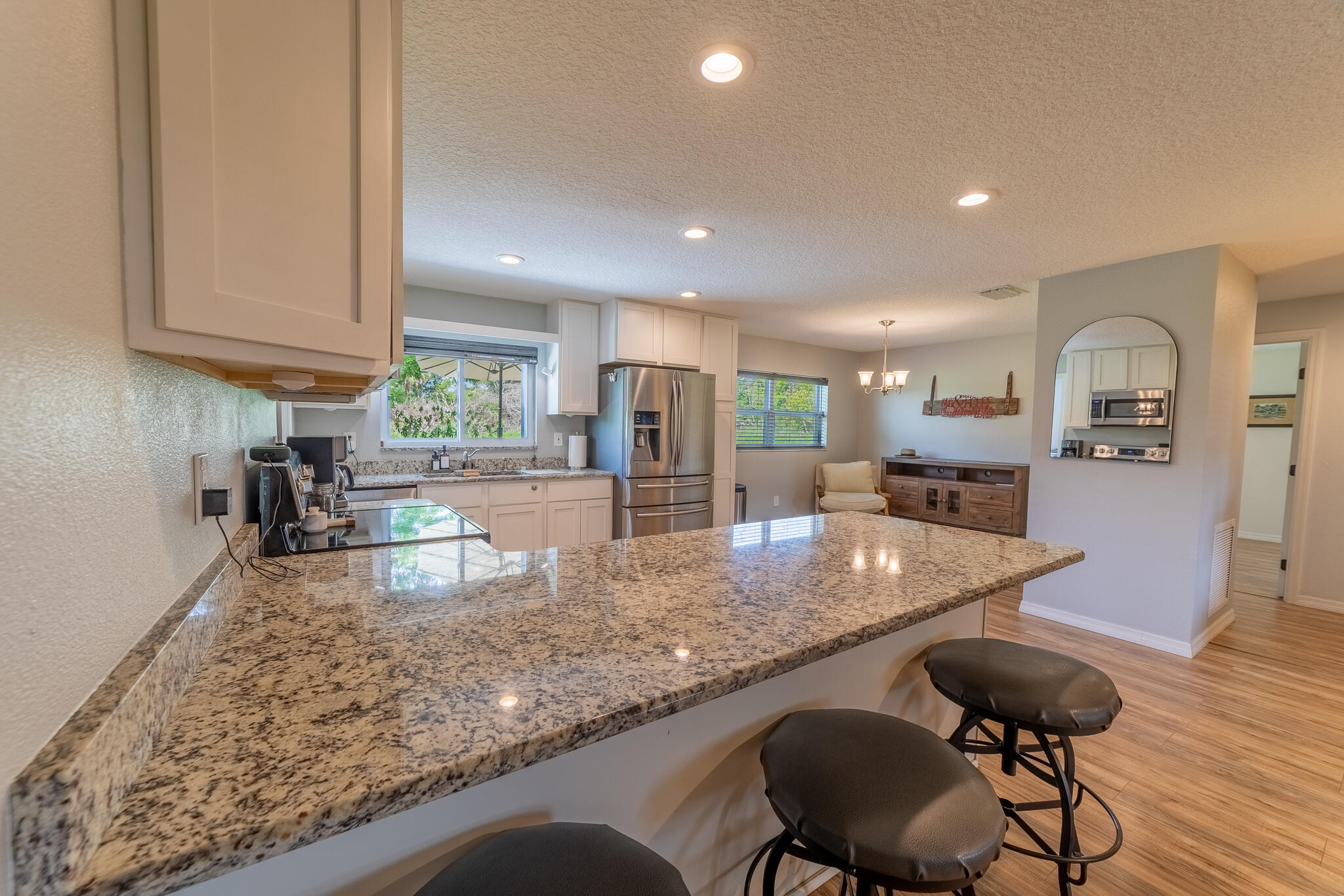 2675 Southwest 24th Avenue Okeechobee, FL 34974 - Photo 56 of 60 a kitchen with stainless steel appliances granite countertop a stove a sink a refrigerator and white cabinets with wooden floor