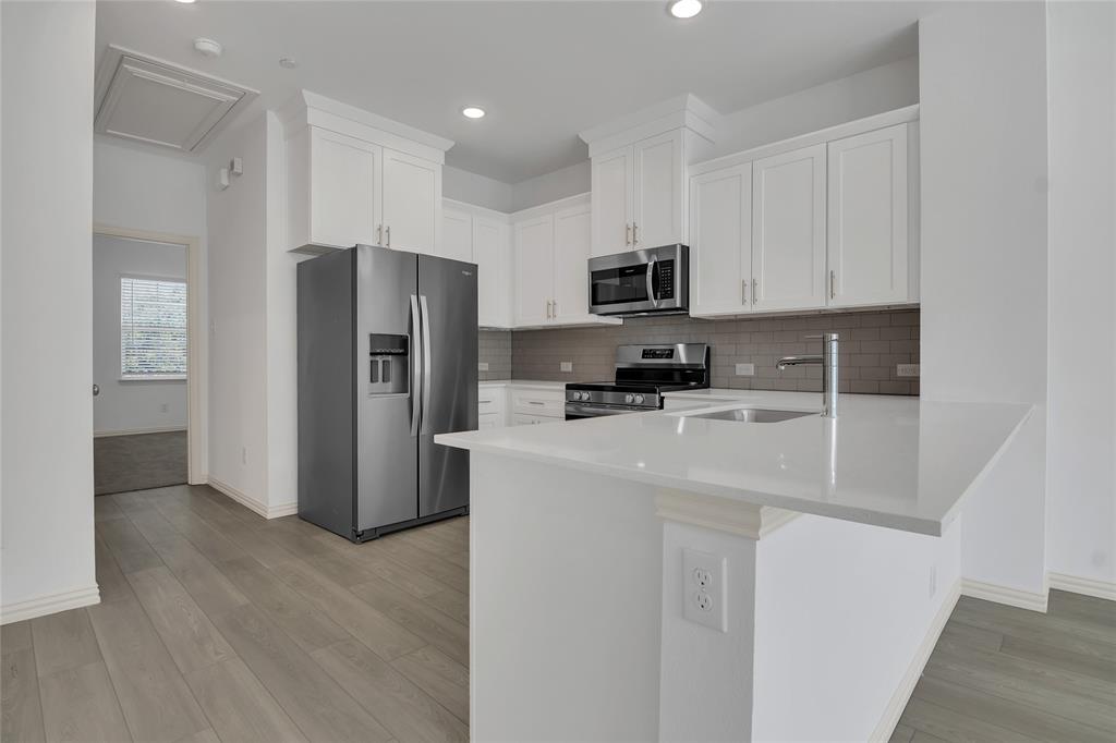 5258 Springlake Parkway Haltom City, TX 76117 - Photo 17 of 24 a kitchen with stainless steel appliances a refrigerator a sink a stove a microwave and cabinets