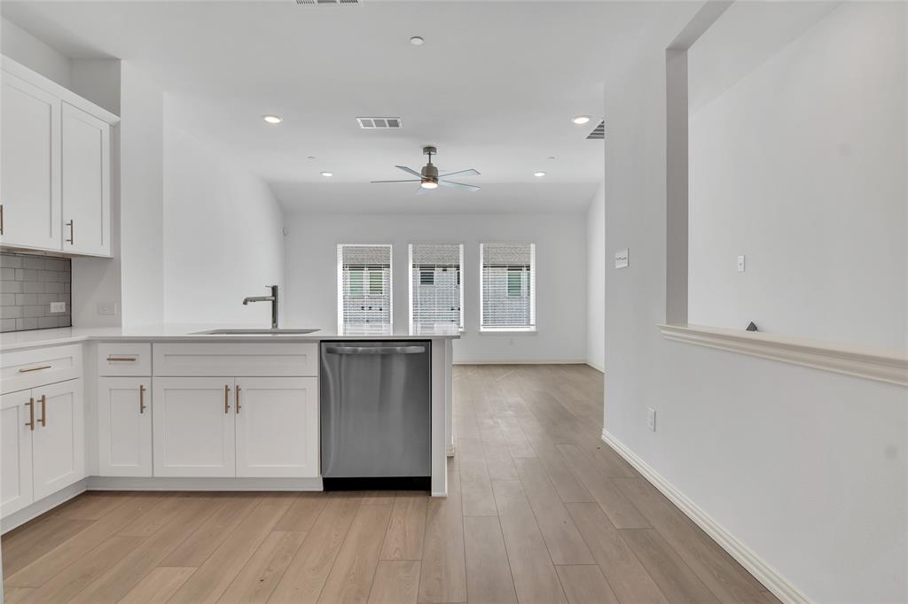 5258 Springlake Parkway Haltom City, TX 76117 - Photo 19 of 24 a large white kitchen with kitchen island a sink dishwasher a stove and white cabinets with wooden floor