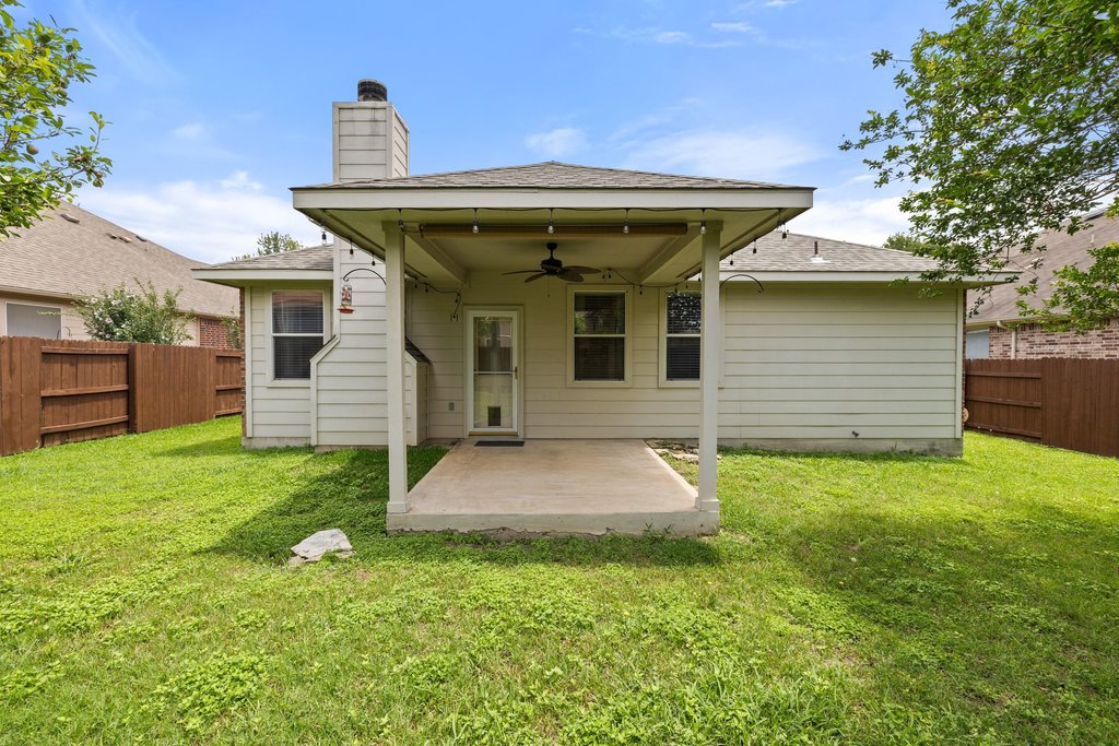 347 Spring Drive Kyle, TX 78640 - Photo 39 of 40 A well-maintained fenced yard offers a welcoming covered patio, perfect for outdoor relaxation.