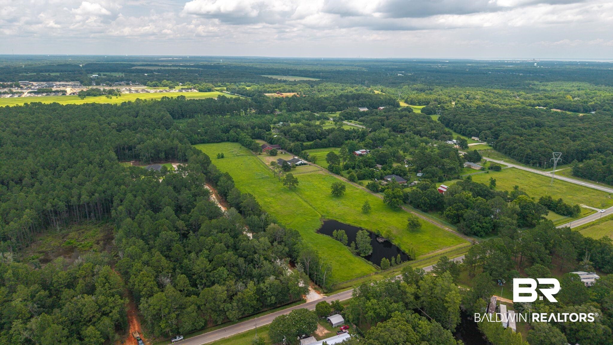 7540 2 Mile Road Irvington, AL 36544 - Photo 78 of 82 Expansive rural property featuring a large wooded area, open grassy fields, a private pond, and a paved road frontage