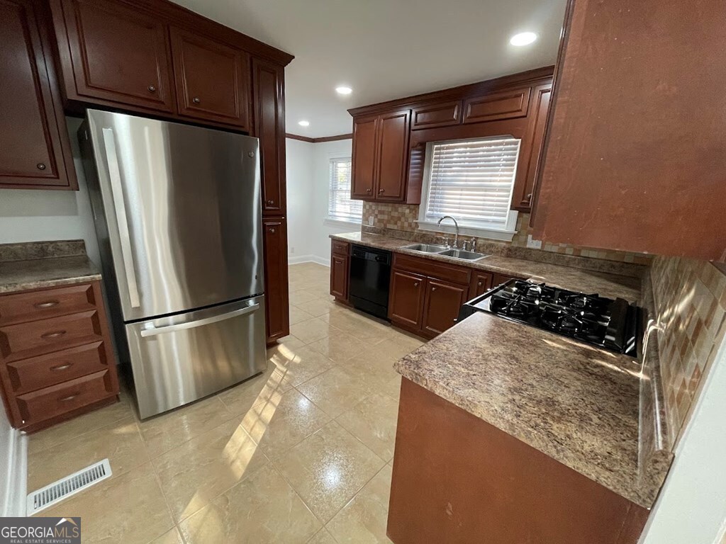 2311 St George Lane Albany, GA 31707 - Photo 14 of 39 a kitchen with stainless steel appliances granite countertop a refrigerator a stove and a sink with wooden cabinets