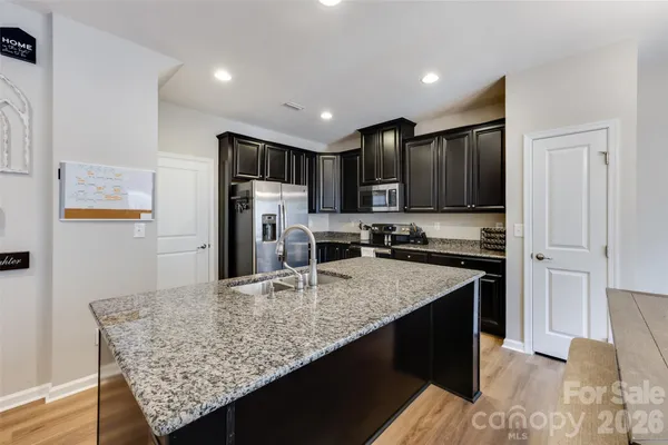 a kitchen with stainless steel appliances granite countertop a sink refrigerator and cabinets