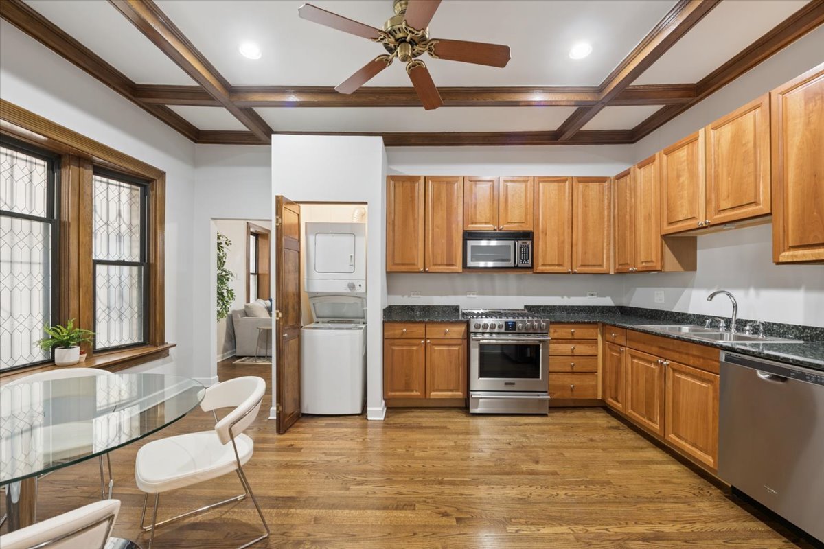 4028 North Sheridan Road, Unit 1R Chicago, IL 60613 - Photo 5 of 15 a large kitchen with stainless steel appliances granite countertop a stove top oven a sink dishwasher a dining table and chairs with wooden floor