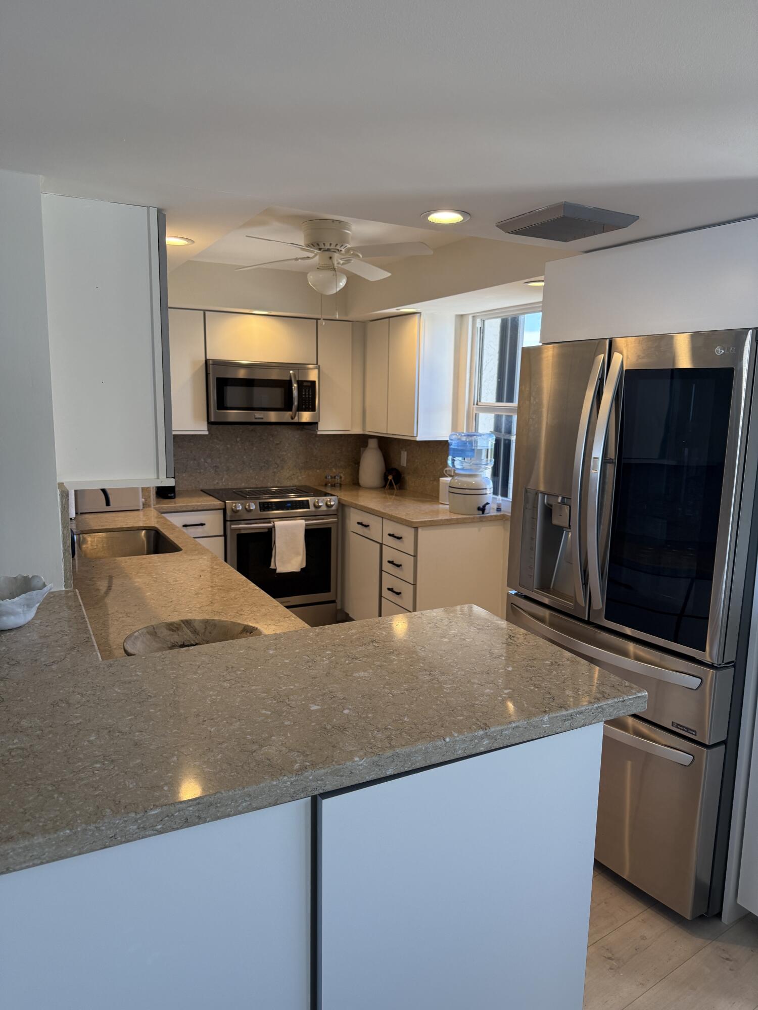 5200 North Flagler Drive, Unit 1406 West Palm Beach, FL 33407 - Photo 9 of 31 a kitchen with stainless steel appliances granite countertop a sink refrigerator and microwave