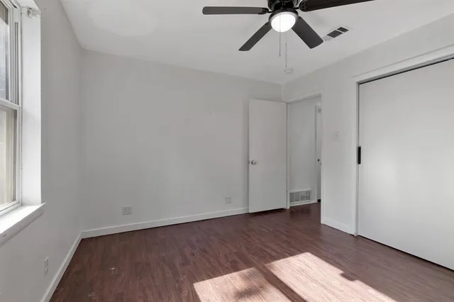 a view of empty room with wooden floor and fan
