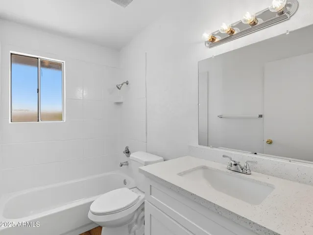 a bathroom with a bathtub shower sink vanity mirror and toilet