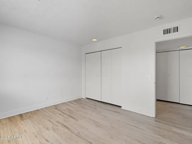 a view of an empty room with wooden floor and a refrigerator
