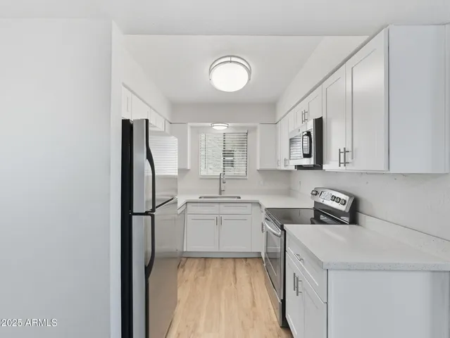 a kitchen with a sink a refrigerator and cabinets