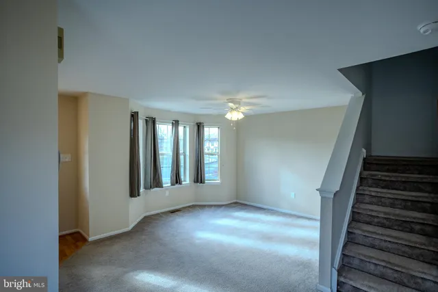 a view of an empty room with wooden floor and stairs