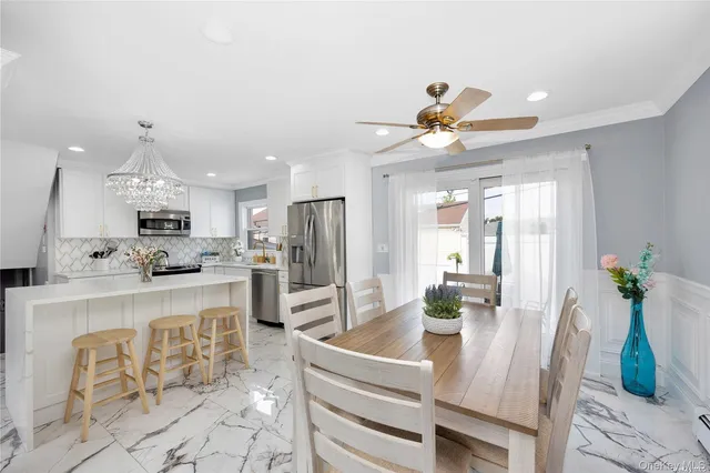 a living room with stainless steel appliances furniture a dining table and kitchen view