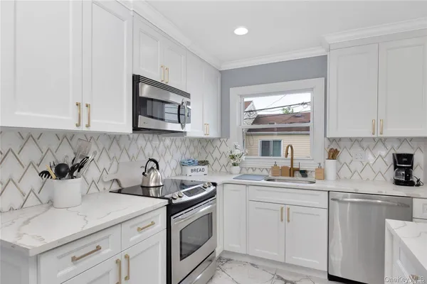a kitchen with stainless steel appliances white cabinets sink and stove top oven