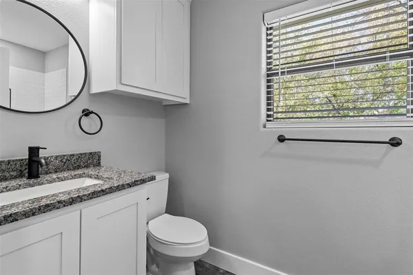 a bathroom with a granite countertop toilet sink and mirror