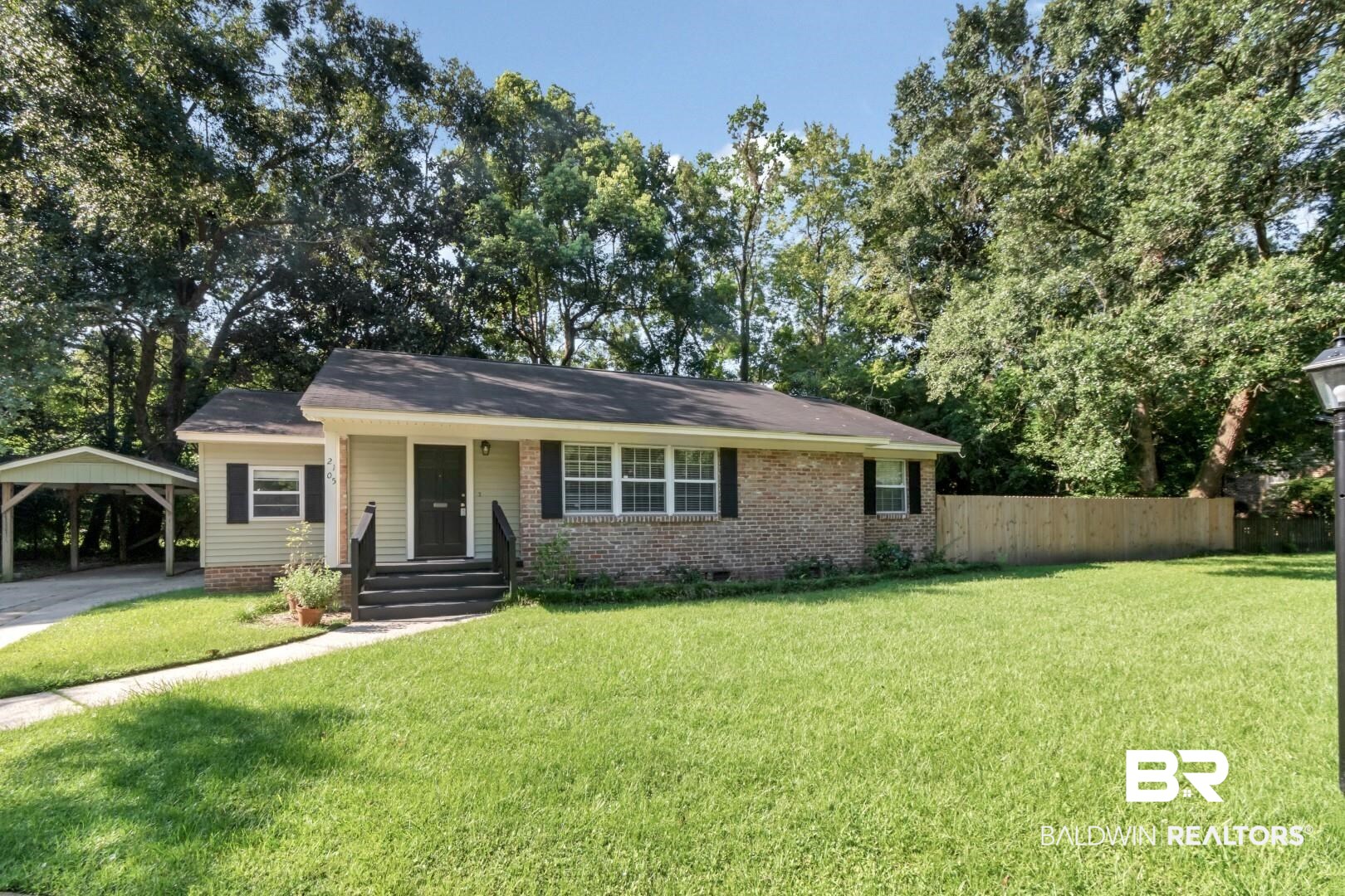 2105 Upham Court Mobile, AL 36607 - Photo 1 of 32 View of front of house with a detached carport, brick siding, a porch, and view of wooded area