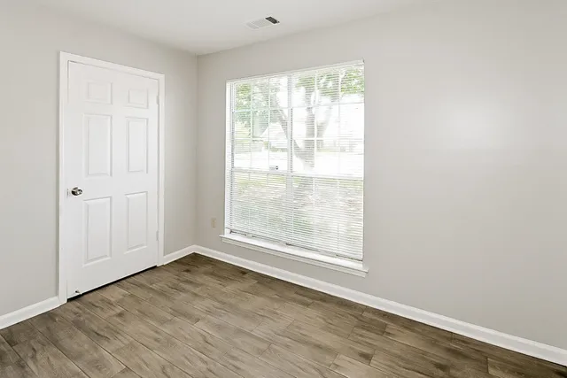 an empty room with wooden floor chandelier fan and windows