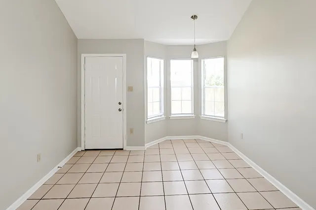 a view of an empty room with wooden floor and window