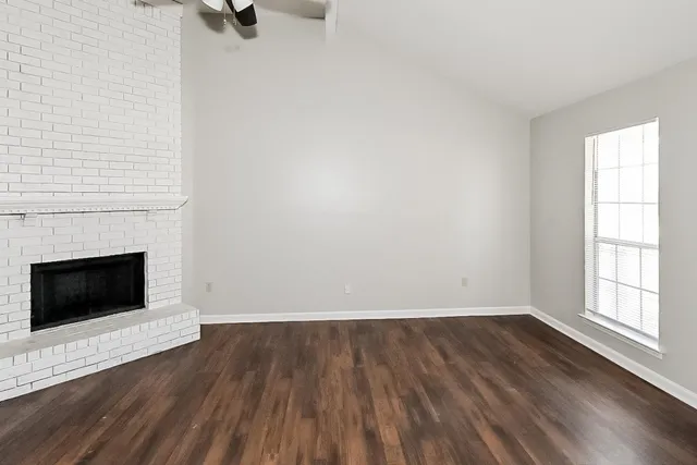 a view of a livingroom with a fireplace a ceiling fan and wooden floor
