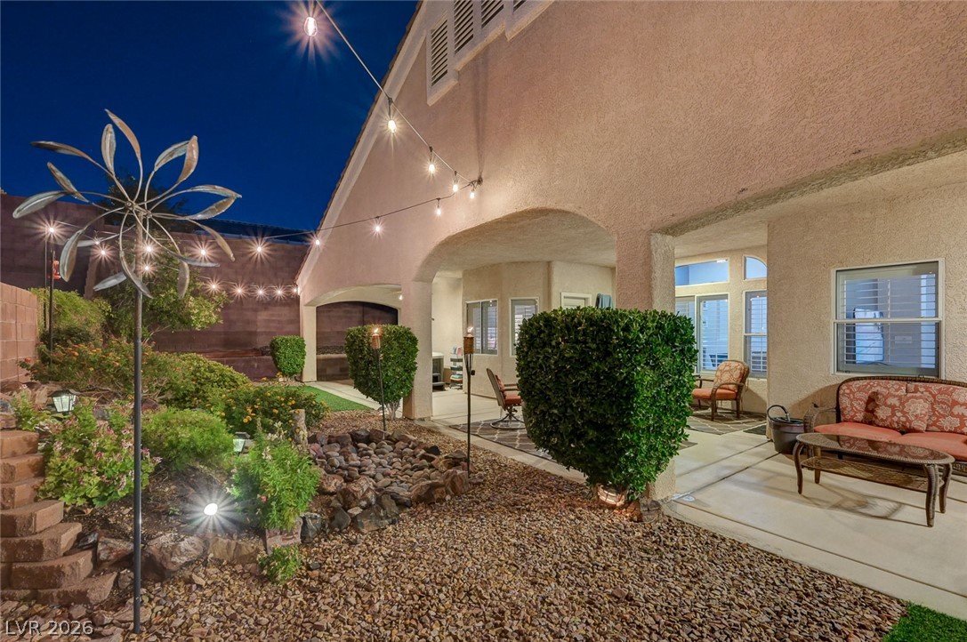 1604 Cattle Ranch Place Henderson, NV 89002 - Photo 7 of 99 A private outdoor space with string lights and lush landscaping, ideal for evening relaxation.