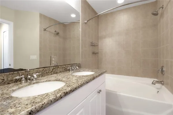 a bathroom with a granite countertop bathtub shower sink and mirror