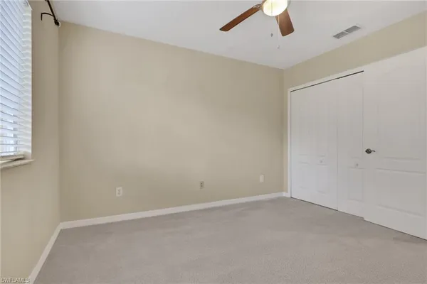 an empty room with ceiling fan and window