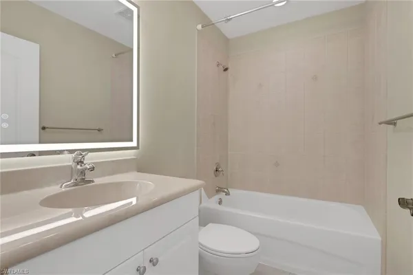 a bathroom with a granite countertop bathtub shower sink vanity mirror and toilet