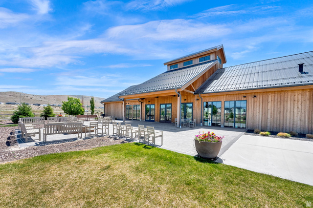 6120 North Sheps Ridge Road Eagle Mountain, UT 84005 - Photo 28 of 43 Expansive outdoor patio with multiple seating areas, a manicured lawn, and a modern wooden building with a metal roof