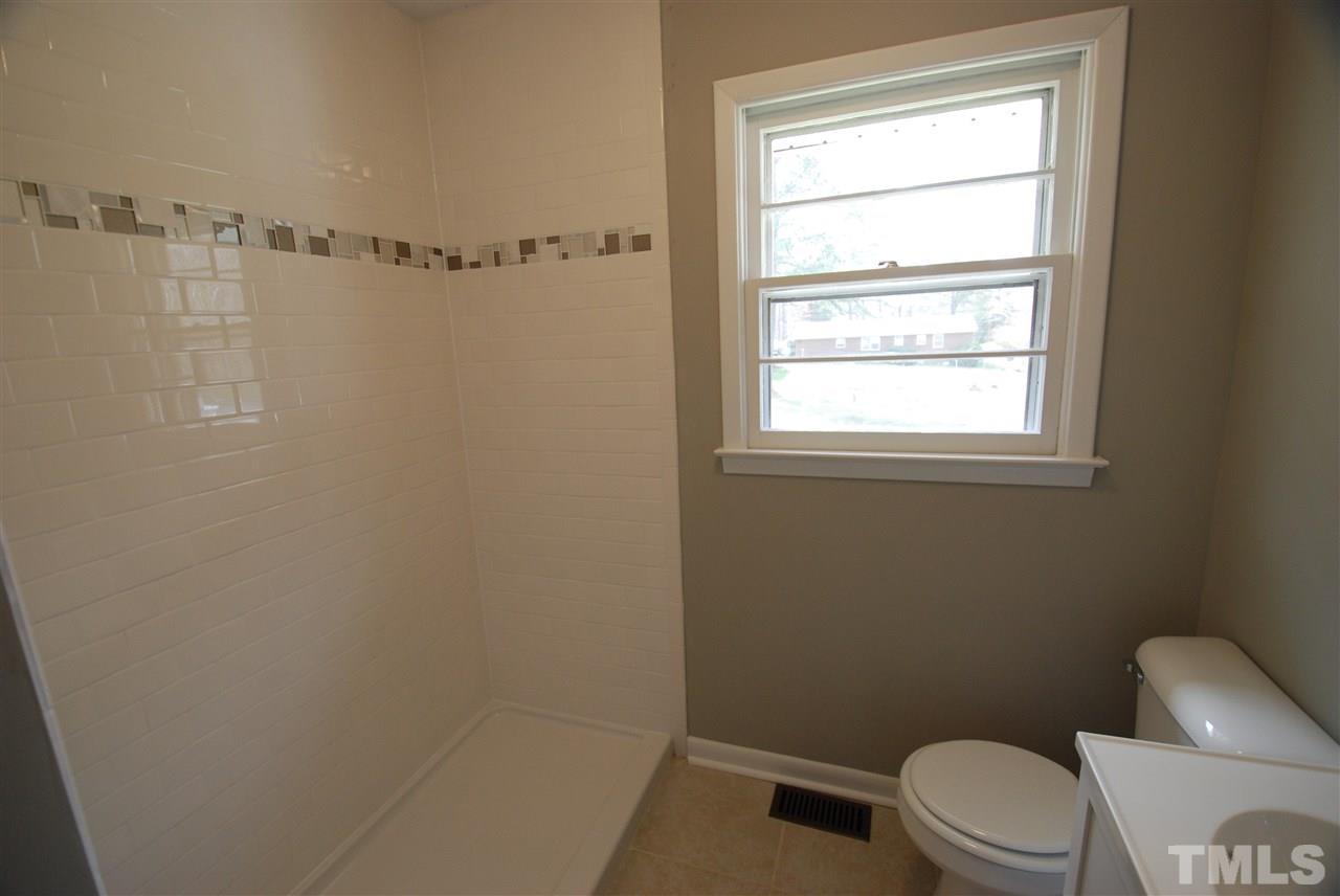 6408 Rock Quarry Road Raleigh, NC 27610 - Photo 13 of 22 Extra Large walk-in shower, new tile with accent stripe, new vanity, and new light fixtures.