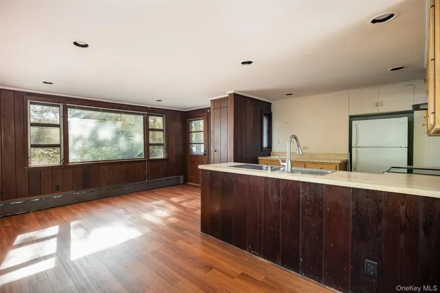 a large kitchen with stainless steel appliances wooden floor and a large window