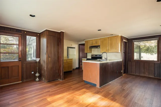 a kitchen with stainless steel appliances granite countertop a refrigerator a sink dishwasher a stove and a dining table with wooden floor