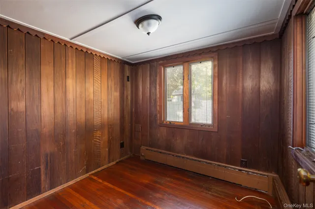 a view of an empty room with a window and hardwood floor