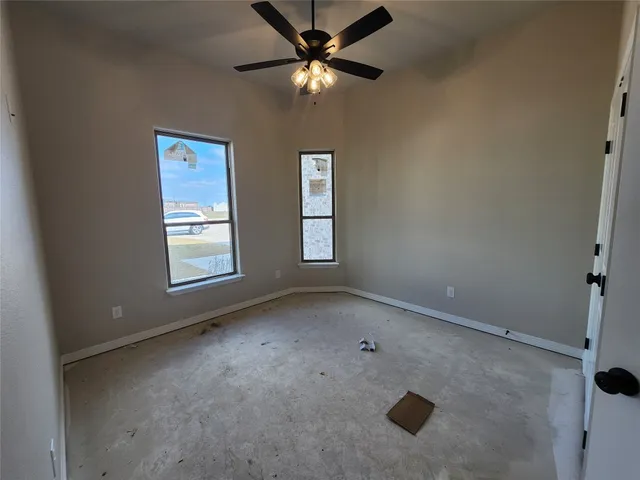 an empty room with windows and fan