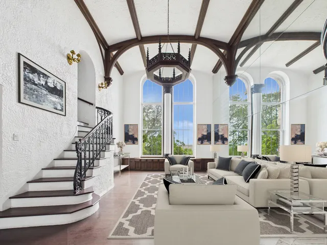 a living room with furniture a large window and a chandelier