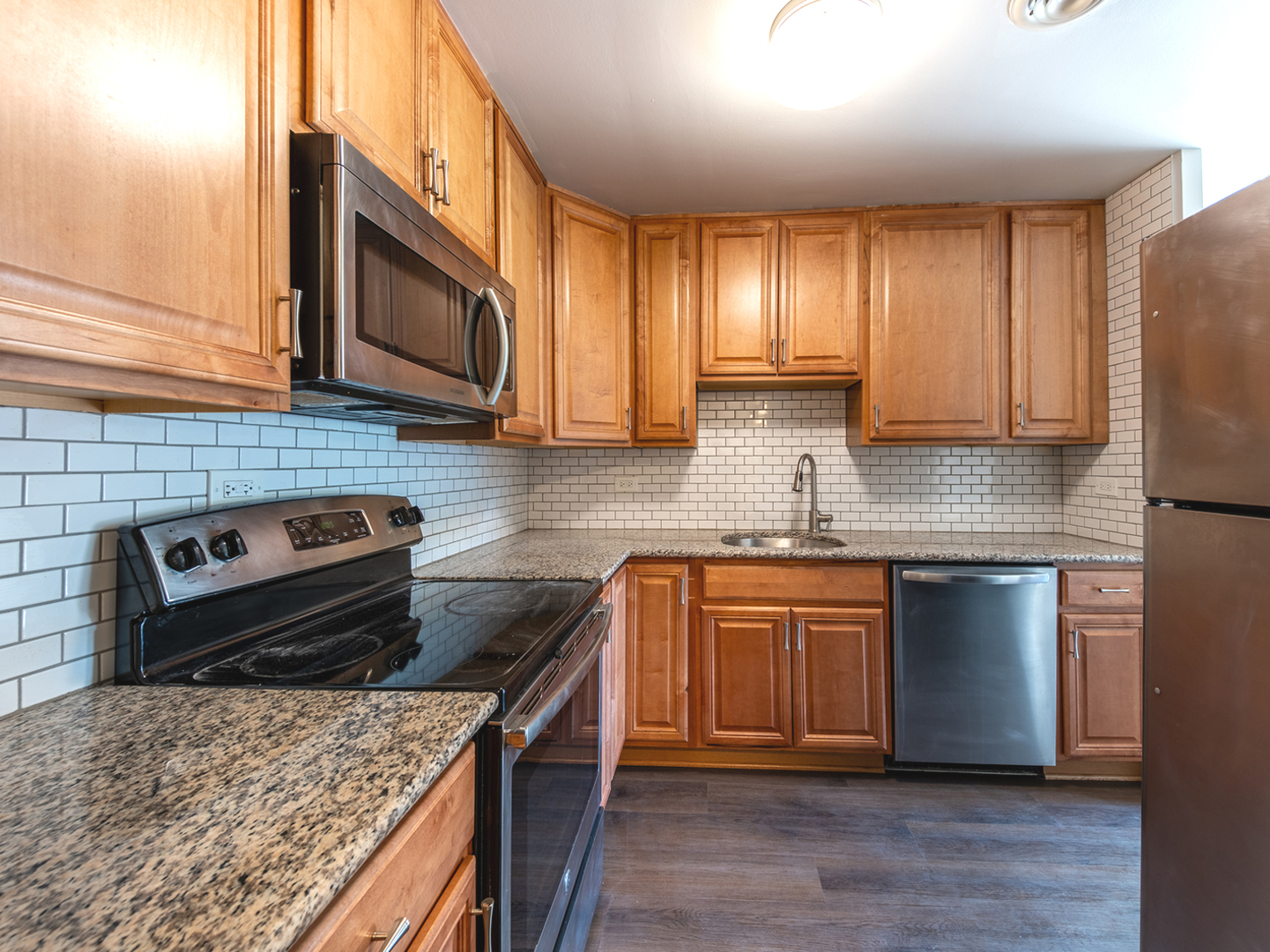 425 Walnut Creek Road, Unit 1207 Lisle, IL 60532 - Photo 4 of 11 a kitchen with stainless steel appliances granite countertop a stove a sink dishwasher and a microwave oven with wooden cabinets