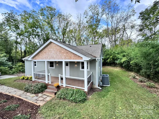 a view of a house with a yard plants and large tree