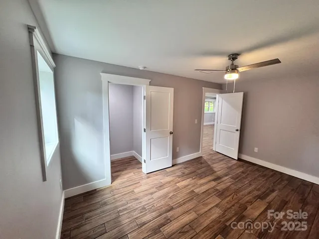 an empty room with wooden floor and windows