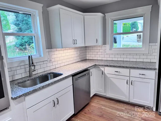 a view of kitchen with stainless steel appliances granite countertop a stove top oven a sink and a refrigerator