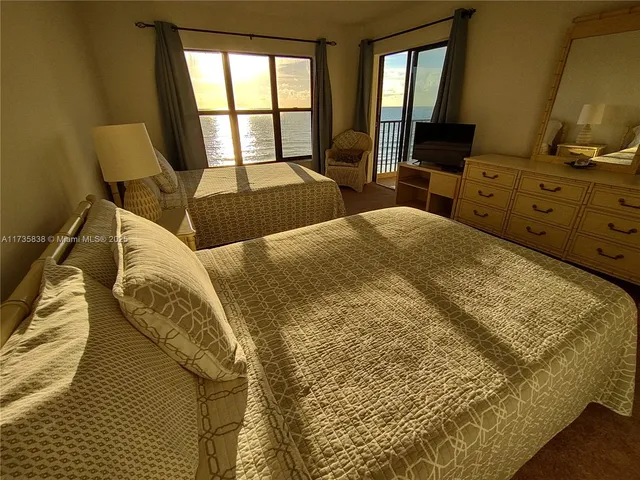 a bed sitting in a bedroom next to a window with pc on the dresser