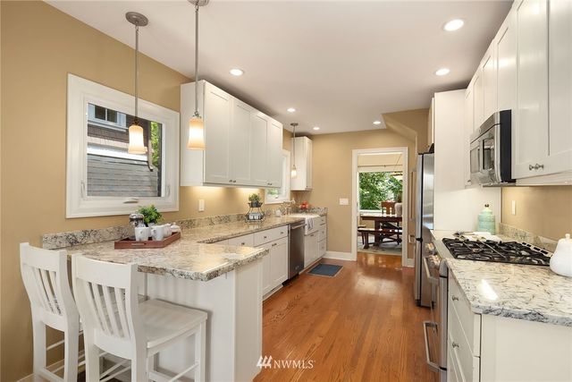 a kitchen with stainless steel appliances kitchen island granite countertop a stove a sink a refrigerator and a dining table with wooden floor