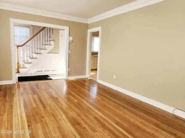 a view of an empty room with wooden floor and a window