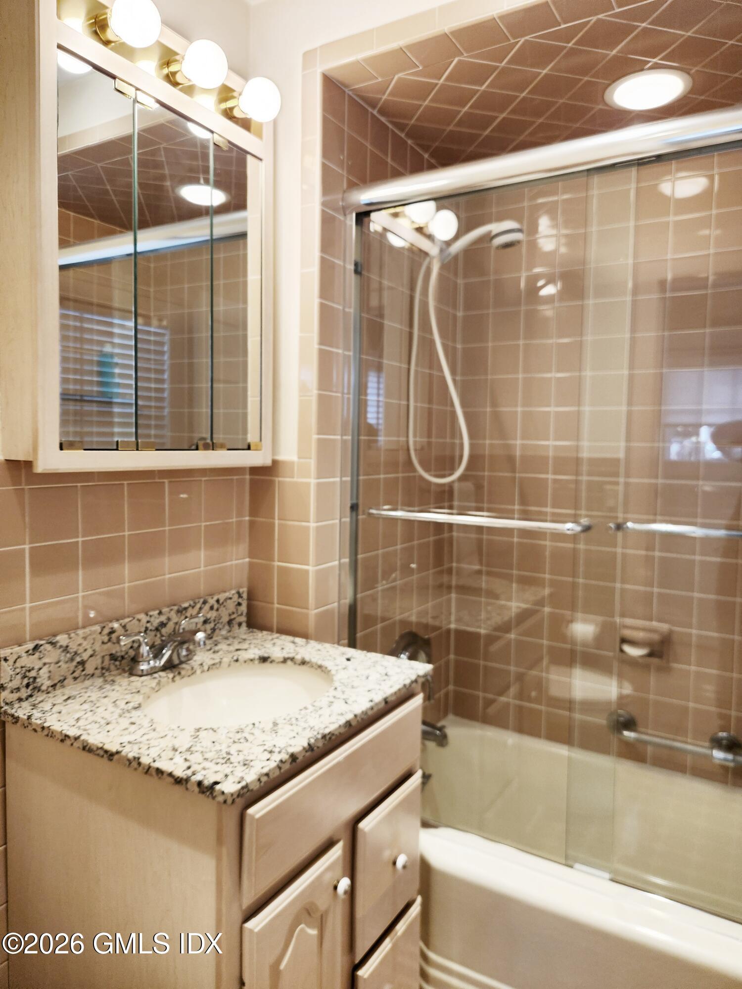 34 Harold Street Cos Cob, CT 06807 - Photo 10 of 25 a bathroom with a granite countertop sink a mirror and a bathtub