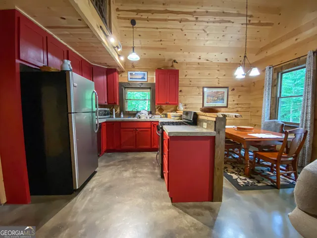 a kitchen with stainless steel appliances granite countertop a refrigerator a sink dishwasher a stove a dining table and chairs with wooden floor