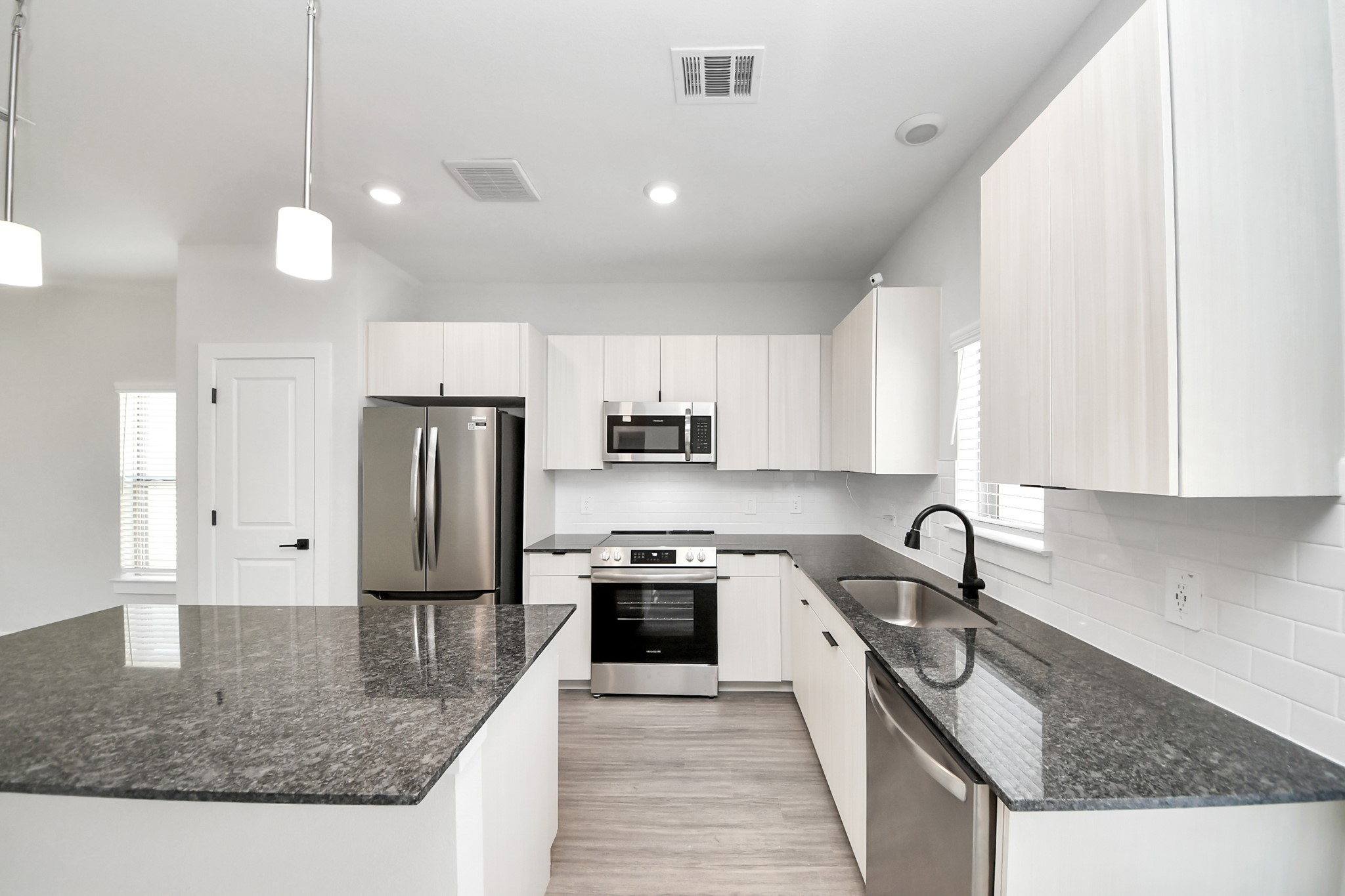 7711 Longmire Road, Unit 5 Conroe, TX 77304 - Photo 38 of 48 Boasting luxury finishes-stylish Island kitchen,granite counters,subway tile backsplash,ample custom cabinet space,stainless appliances,refrigerator,full size washer&dryer included,wood-like flooring throughout,open concept floor plan.